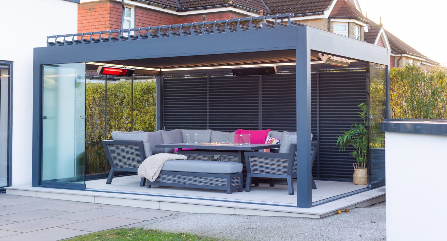 Grey aluminium pergola with louvred side blinds and glass sliding doors fitted against a house extension