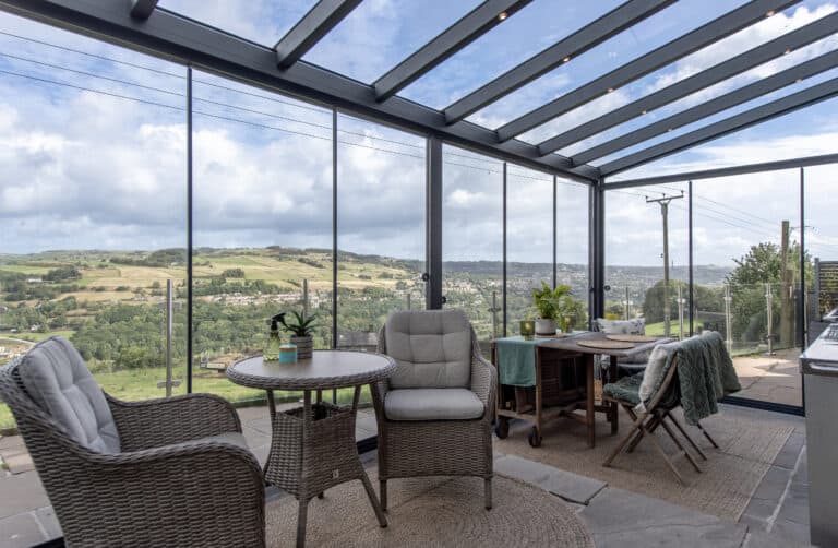 Glass veranda interior with wicker seating overlooking the West Yorkshire countryside, Huddersfield