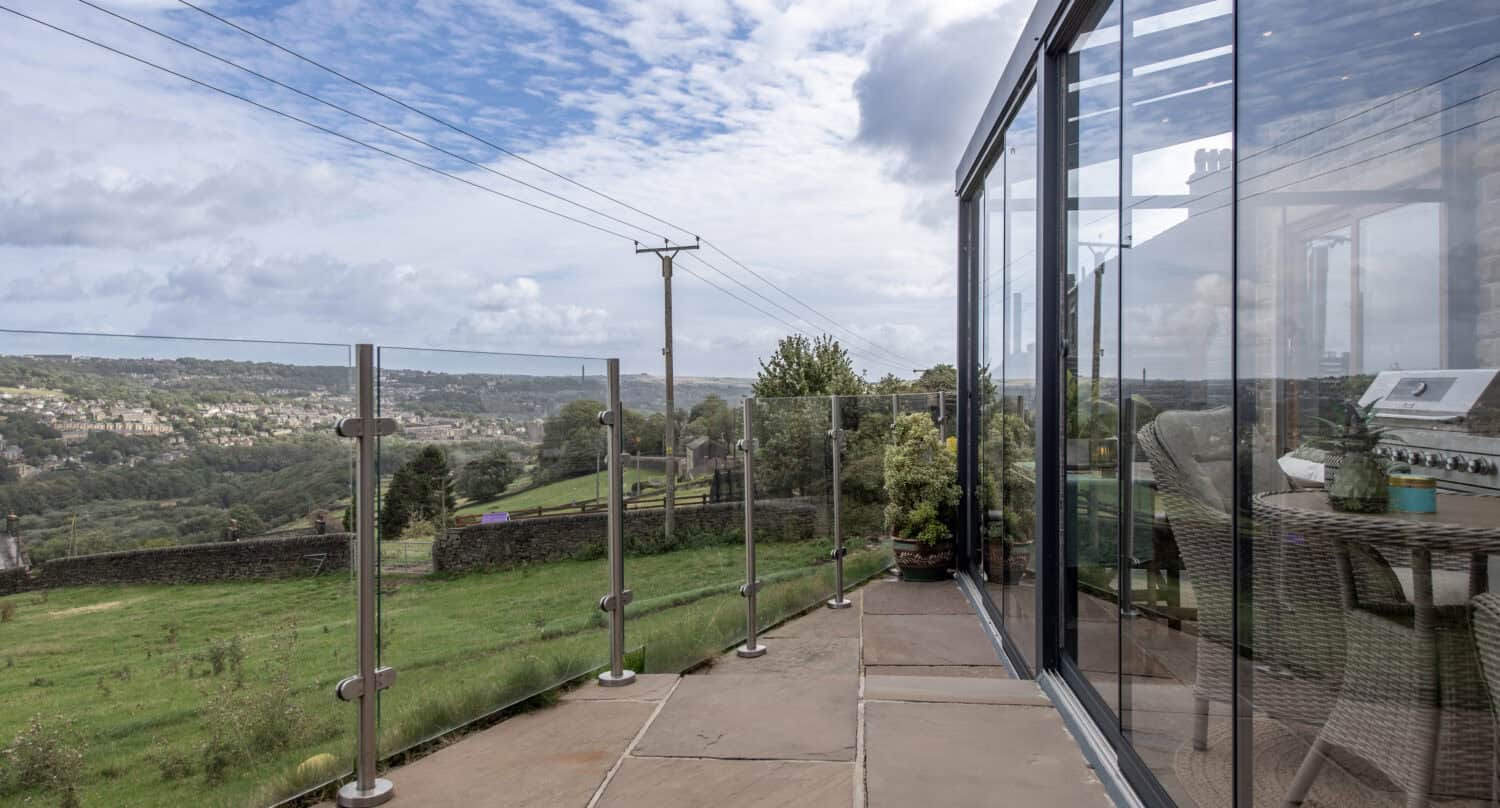 Outdoor dining table inside a glass veranda extension with far reaching views