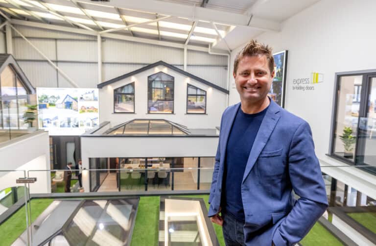 A man posing in a balustrade balcony with a view to the rest of the bifold doors showroom