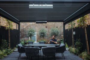 George Clarke sitting at his outdoor dining table under his bioclimatic pergola